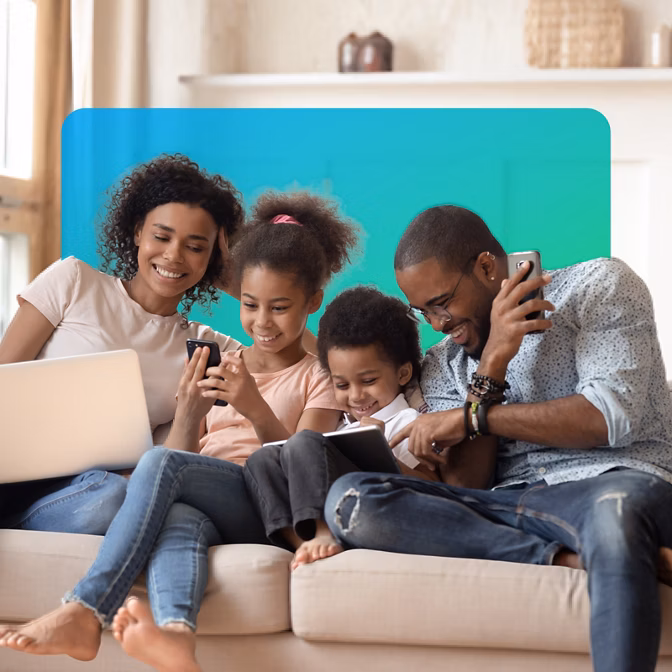 family-sitting-on-couch-in-living-room-looking-at-mobile-devices-with-blue-green-box-in-bg